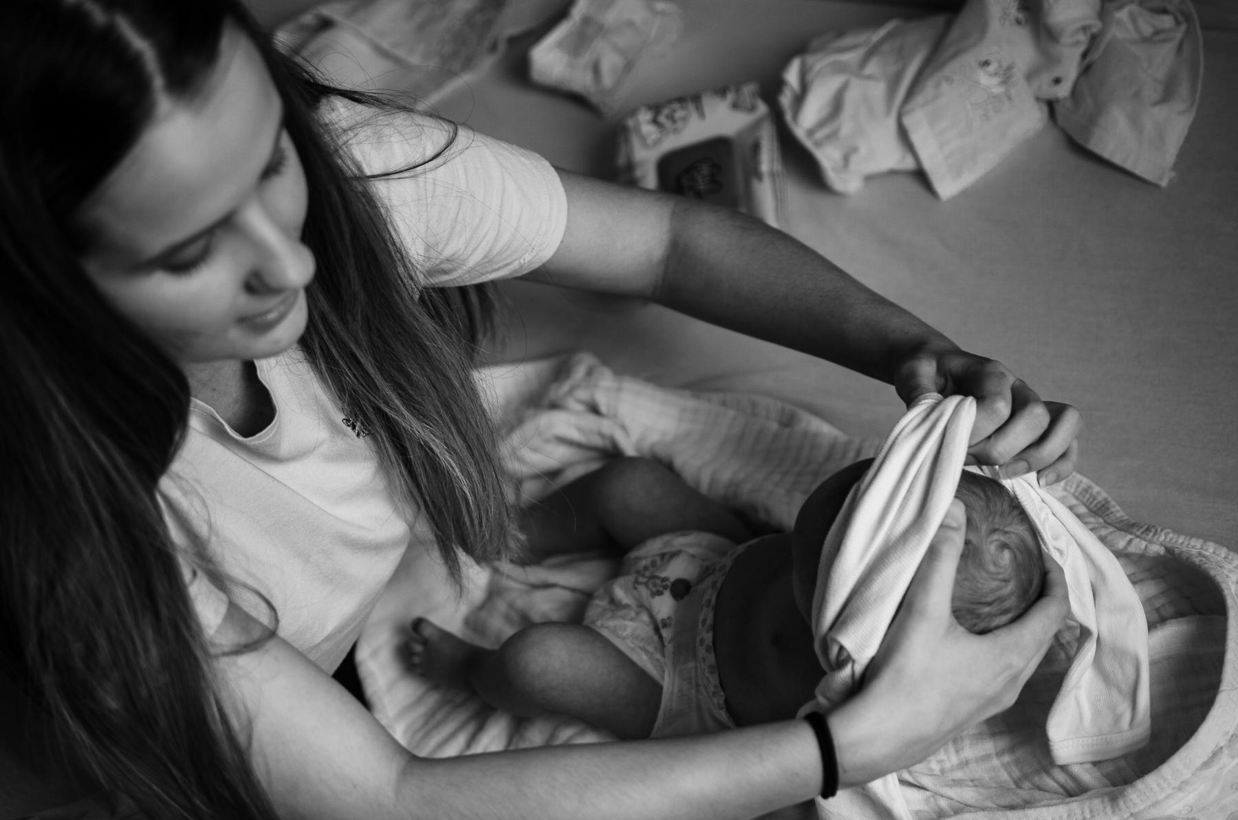 A woman gently dressing a newborn